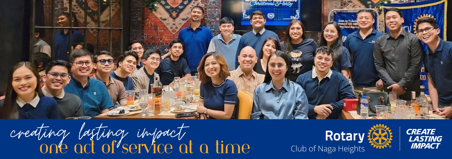 Rotary Club of Naga Heights members celebrating together at a club Christmas party, with the club's Create Lasting Impact theme banner.